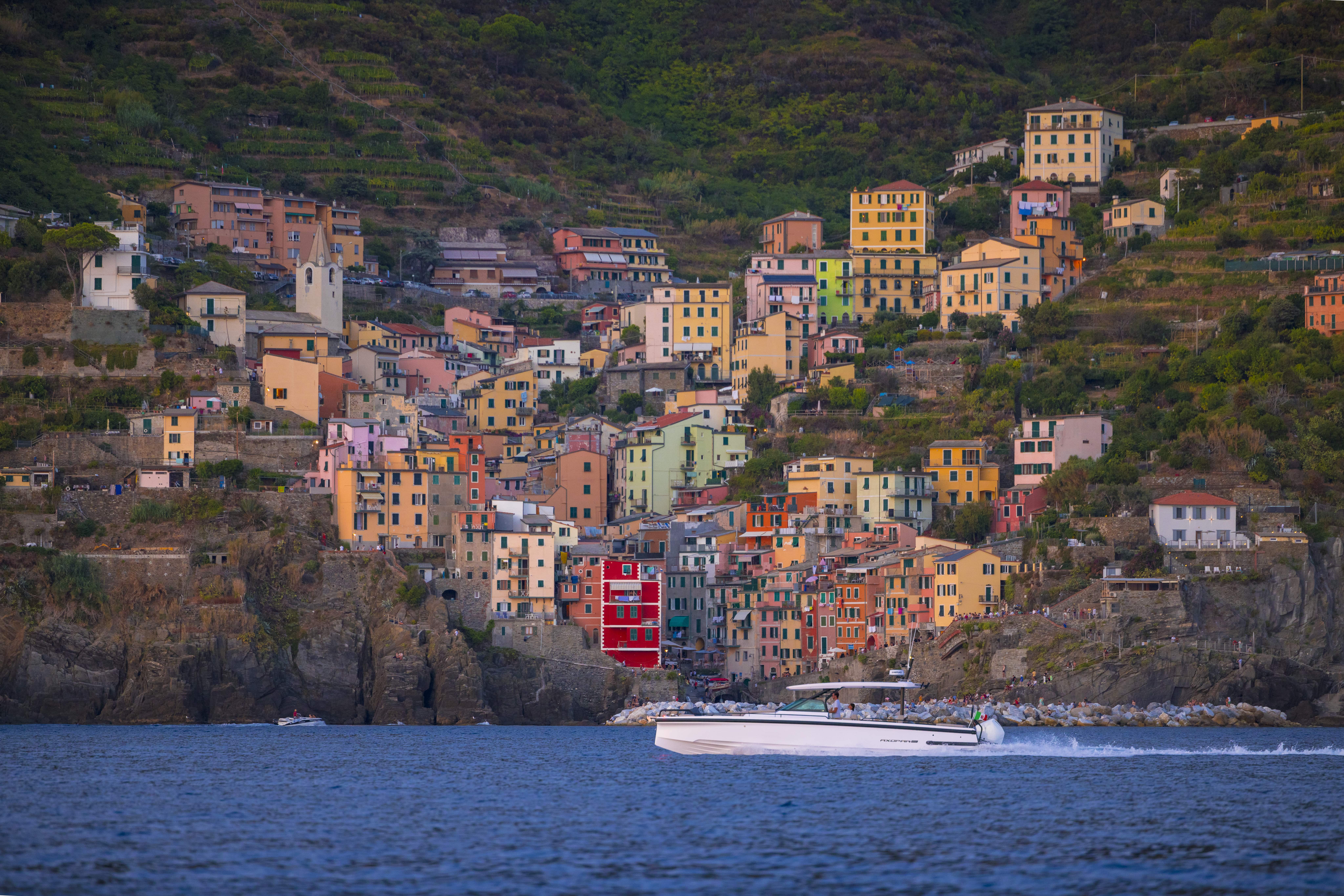 Scenic view of the La Spezia coastline with colorful buildings and boats, framed by lush hillsides.